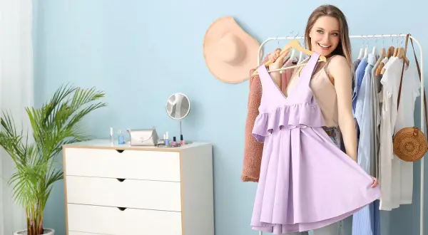 Ragazza sorridente prova un abito color glicine, pensando ai possibili abbinamenti vestiti per un look primaverile.