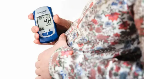 Gravid kvinna kontrollerar sitt blodsocker med en glukosmätare. En viktig del av att hantera graviditetsdiabetes.