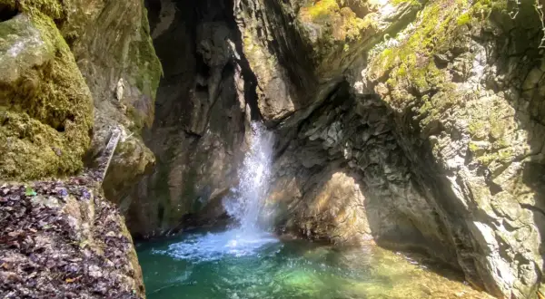 Piccola cascata in una gola rocciosa, con acqua cristallina che forma una pozza. Un luogo incantevole vicino al Lago di Garda.