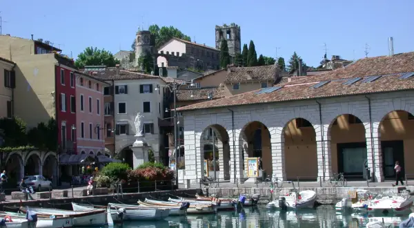 Porto di Desenzano: cosa vedere? Barche ormeggiate, case colorate e torri antiche sul lago.