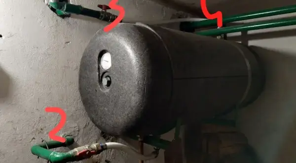 Bojler z termometrem i instalacją hydrauliczną. Widoczny odpowietrznik bojlera, zawory i rury.