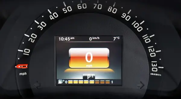 Wyświetlacz cyfrowy na desce rozdzielczej pokazuje 0 mph, 0 km/h, 7°C i godzinę 10:45. To korekta przebiegu po wymianie licznika.