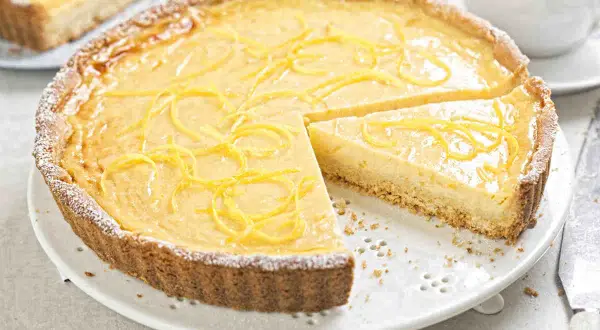 Una deliziosa crostata con crema pasticcera, guarnita con scorza di limone e spolverata di zucchero a velo.