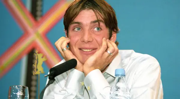 Cillian Murphy, znany z wielu filmów, z niebieskimi oczami i dłońmi opartymi o twarz, podczas konferencji prasowej.