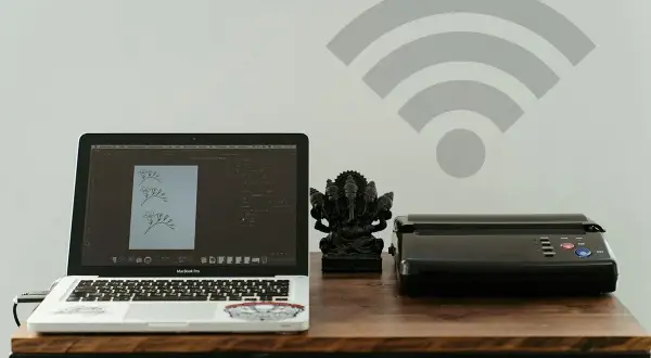 Dowiedz się, jak dodać drukarkę do telefonu, by bezprzewodowo drukować z laptopa i innych urządzeń. Na biurku laptop, drukarka i figurka Ganeszy.