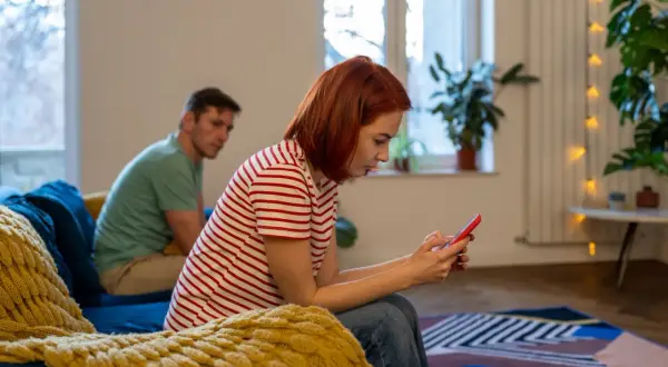 Kobieta z rudymi włosami, jak toksyczna siostra, ignoruje mężczyznę, skupiając się na telefonie.