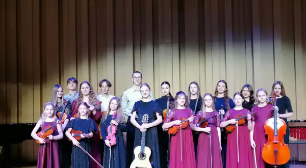 Młodzi muzycy, w tym Aleksandra Cieślik, gotowi do występu z instrumentami smyczkowymi i gitarą.