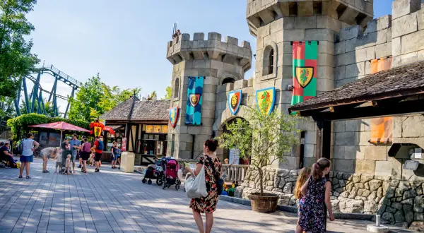 Rodzina zwiedza zamek w Legolandzie, zastanawiając się, czy to Legoland Niemcy czy Dania. W tle widać kolejkę górską.