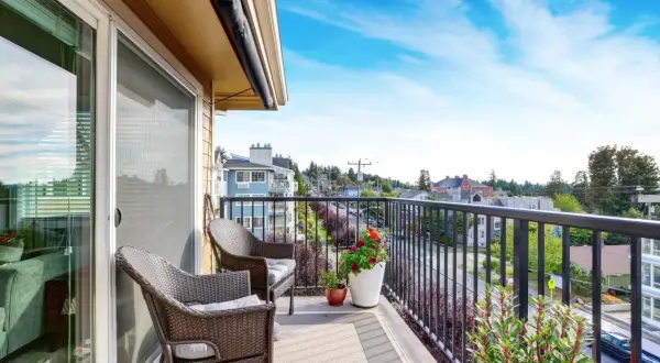 Uroczy balkon z wygodnymi meblami i kwitnącymi kwiatami. Jasne kafle na balkon tworzą przytulną atmosferę.