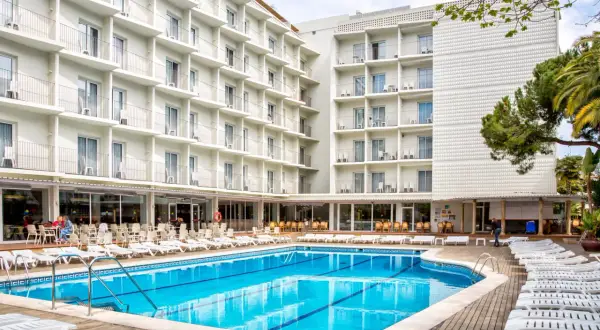 Basen i leżaki przy hotelu Don Juan Resort. Wiele białych balkonów hotelowych z widokiem na basen.