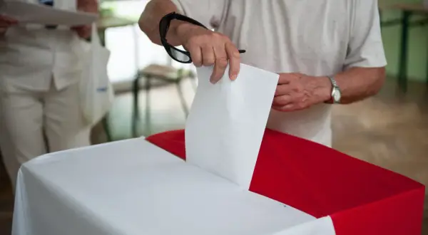 Mężczyzna wrzuca kartę do głosowania do urny. To ważny moment, nawet jeśli są to wybory poza miejscem zamieszkania.