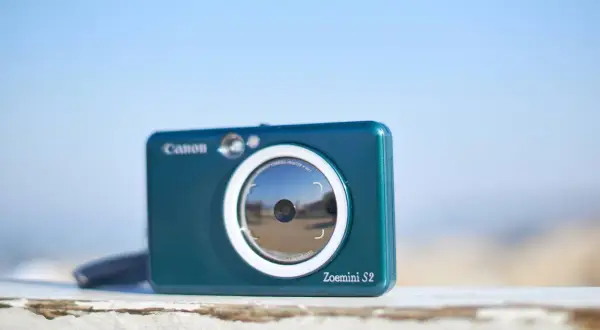 Niebieski aparat Canon Zoemini S2, idealny aparat na wakacje, gotowy do łapania wspomnień.