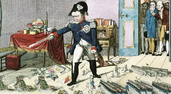 Napoleón, con su característico sombrero, parece medir su estatura en medio de un caos de mapas y soldados en miniatura.