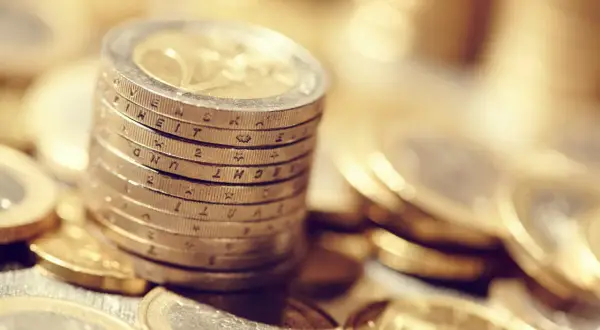 Pile de pièces en euros, certaines gravées de la marque APC, symbolisant la richesse et l'épargne.