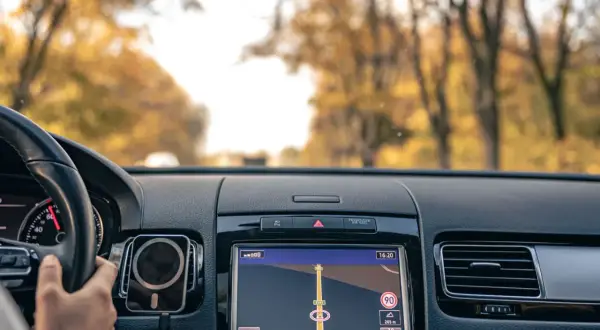 Widok z wnętrza samochodu na nawigację GPS. Kierowca trzyma kierownicę, a ekran pokazuje trasę. To dobry moment, by pomyśleć, jak zaktualizować GPS.