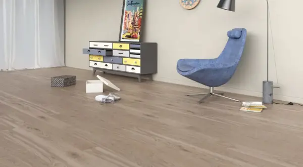 Drewniana podłoga w kolorze taupe, jaki to kolor? W pokoju stoi niebieski fotel, szafka z kolorowymi szufladami i lampa.