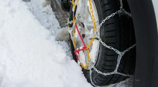Łańcuchy na kołach 4x4 poprawiają przyczepność na śniegu. Widać je na oponie w zaspie.
