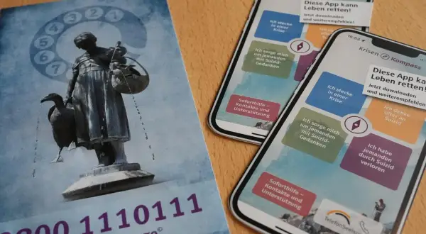 Flyer und Smartphones mit der App "Krisen Kompass" zeigen Wege zur rettung aus der not. Die Telefonseelsorge bietet Hilfe.