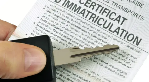 Clé de voiture sur un certificat d'immatriculation, symbolisant les documents d'achat d'une voiture d'occasion.