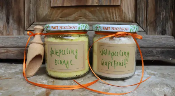 Zwei Gläser mit selbstgemachtem Saunasalz (Orange & Grapefruit) und eine Holzschaufel, verziert mit orangefarbenen Bändern.