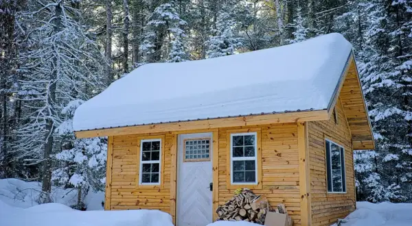 Drewniany domek letniskowy całoroczny w zimowej scenerii. Zastanawiasz się, ile kosztuje budowa domku letniskowego całorocznego?