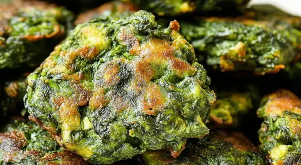 Buñuelos de espinacas dorados y crujientes, apilados en un plato. Un bocado delicioso y saludable.