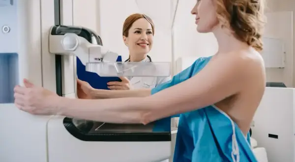 Kobieta na mammografii, pielęgniarka z uśmiechem obok. Co dalej po złym wyniku mammografii?