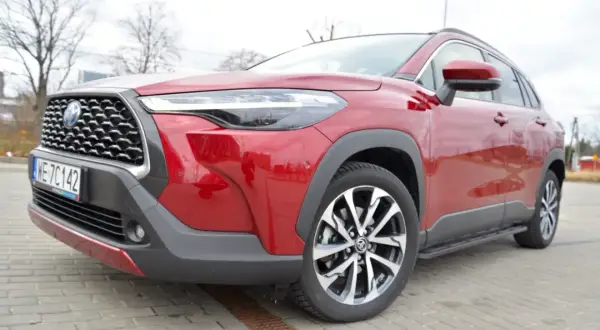 Czerwona Toyota Corolla Cross na zdjęciu prezentuje się imponująco, a jej wysoki prześwit sugeruje gotowość do pokonywania różnych dróg.