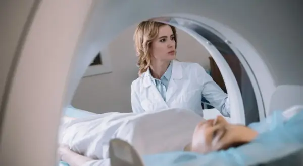 Lekarka nadzoruje badanie rezonans serca. Pacjent leży na stole aparatu MRI.