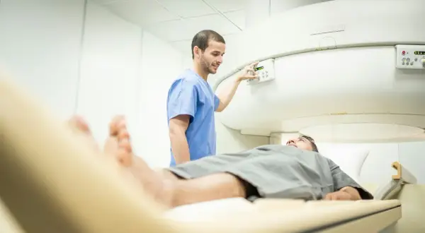 Un technicien ajuste les commandes d'un appareil d'IRM, prêt à examiner la prostate d'un patient allongé sur la table d'examen.