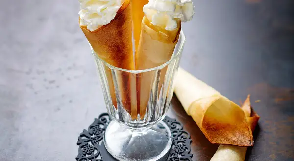 Délicieux cornets croustillants garnis de crème chantilly aérienne, prêts à être dégustés.