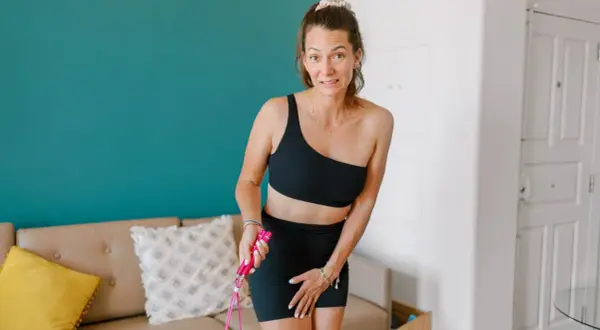 Femme en tenue de sport, inquiète, tenant une corde à sauter. Elle semble se demander "fuites urinaires que faire ?".