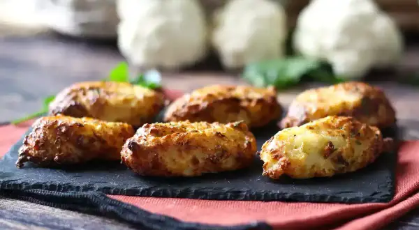 Krispiga blomkålsbiffar på en svart skifferplatta, ett perfekt middagstips för en hälsosam och god måltid.