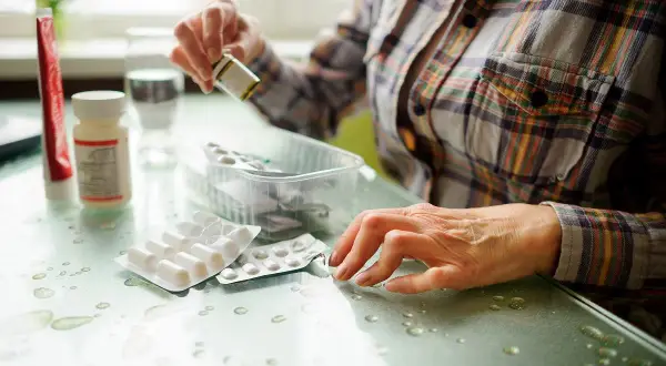 Kobieta przygotowuje się do leczenia biologicznego RZS, biorąc leki z opakowań.