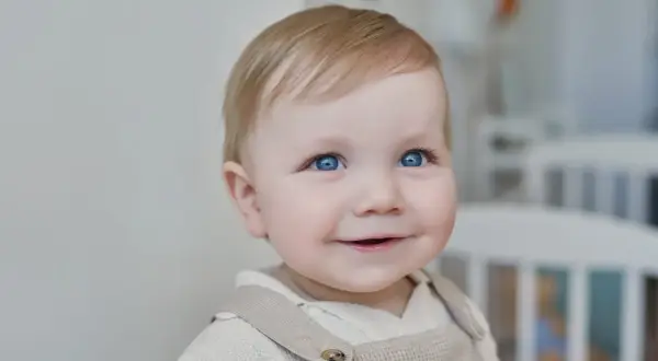 Un bébé aux yeux bleus pétillants sourit, prêt pour sa lettre demande de place en crèche urgent.