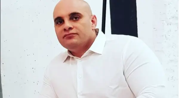 Dominik Abus, wiek nieznany, w białej koszuli, na tle białej ściany z czarnymi pasami.