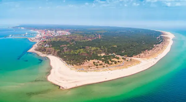 Półwysep Helski zachwyca szerokością plaż i lasów. Widok na miasteczko i turkusowe morze.