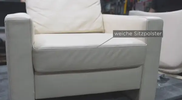 Ein weißer Ledersessel mit weichen Sitzpolstern. Hier wird gezeigt, wie man den Federkern eines Sofas reparieren kann.