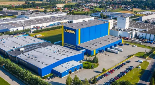 Widok z lotu ptaka na fabrykę Lakma z niebiesko-żółtymi budynkami i parkingiem.