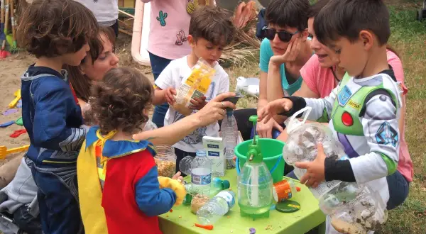 Niños disfrutan de actividades infantiles al aire libre, jugando con materiales reciclados y aprendiendo.