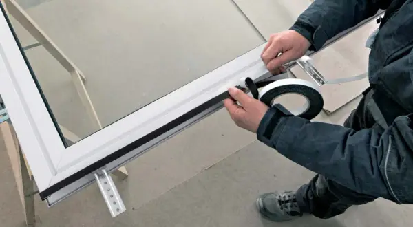 Pose porte fenêtre : application d'un joint d'étanchéité sur le cadre d'une fenêtre en aluminium.