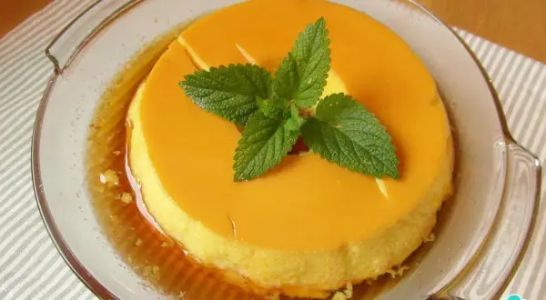 Delicioso flan de leche condensada al baño maría, decorado con hojas de menta fresca.