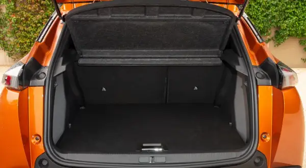 Bagagliaio aperto di una Peugeot 2008 arancione. Le dimensioni sono adatte per un weekend fuori porta.