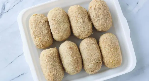 Ocho croquetas empanadas listas para cocinar en la airfryer.