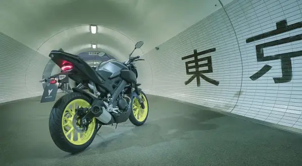 Yamaha MT-125 gris con llantas amarillas en un túnel con caracteres japoneses. ¡Lista para alcanzar su yamaha mt 125 velocidad maxima!