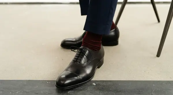 Eleganckie, czarne półbuty męskie na sznurówki, które powinien mieć w domu każdy mężczyzna, w połączeniu z bordowymi skarpetkami.
