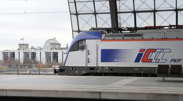 PKP Intercity Zug mit dem Logo "IC" und "PKP" steht am Bahnsteig. Im Hintergrund das Reichstagsgebäude in Berlin. Neue Zugverbindung Berlin - Krakau.