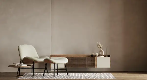 A minimalist living room with a textured limewash wall, a modern chair and ottoman, and a floating media console.