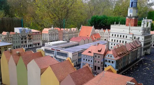 Miniaturowa zabudowa miejska z wieżą zegarową i kolorowymi domkami w skansenie.