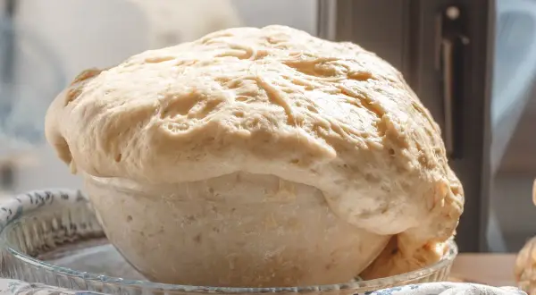 Wyrośnięte ciasto drożdżowe w szklanej misie, gotowe do pieczenia. Idealne na ciasto drożdżowe przepis.